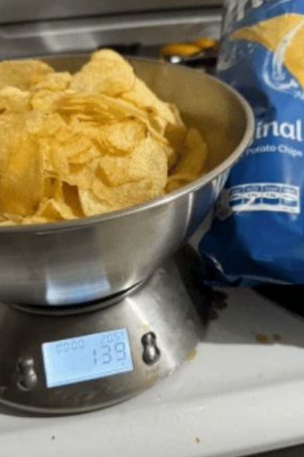 Potato chips in a scale next to a blue bag. 