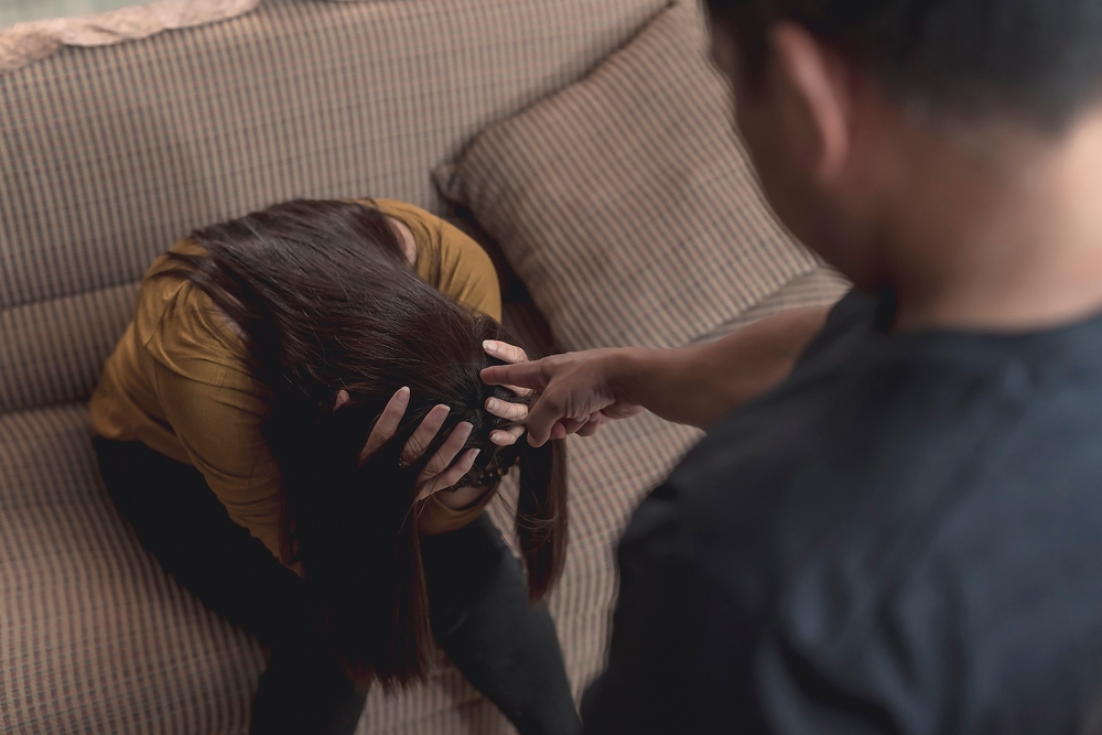 An abusive and manipulative husband points at his emotionally battered wife, making threats and insults. Example of emotional and verbal abuse, or gaslighting.
