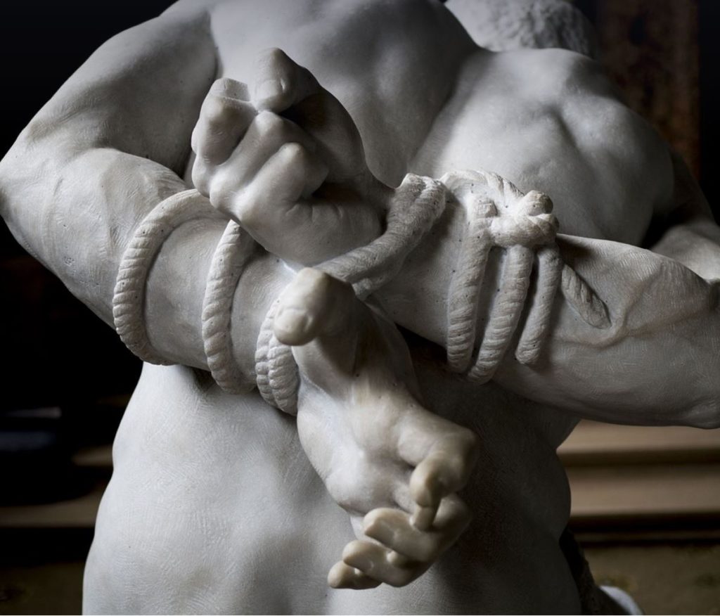 Marble statue of a man tied in ropes. 