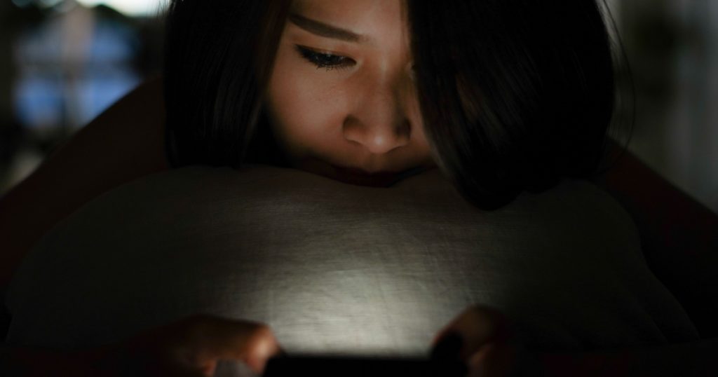 Lonely woman sleepless chat play game or use social media mobile app with smartphone in the dark late night on the bed while self quarantine and stay home