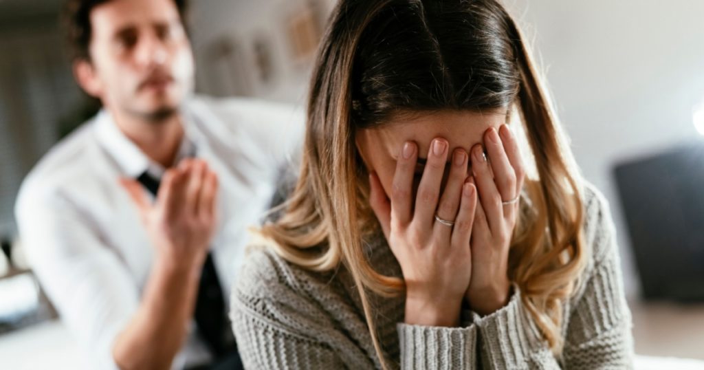Boyfriend and girlfriend are arguing at home. Angry man is yelling at his sad girlfriend.