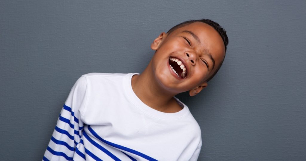Close up portrait of a happy little boy smiling on gray background