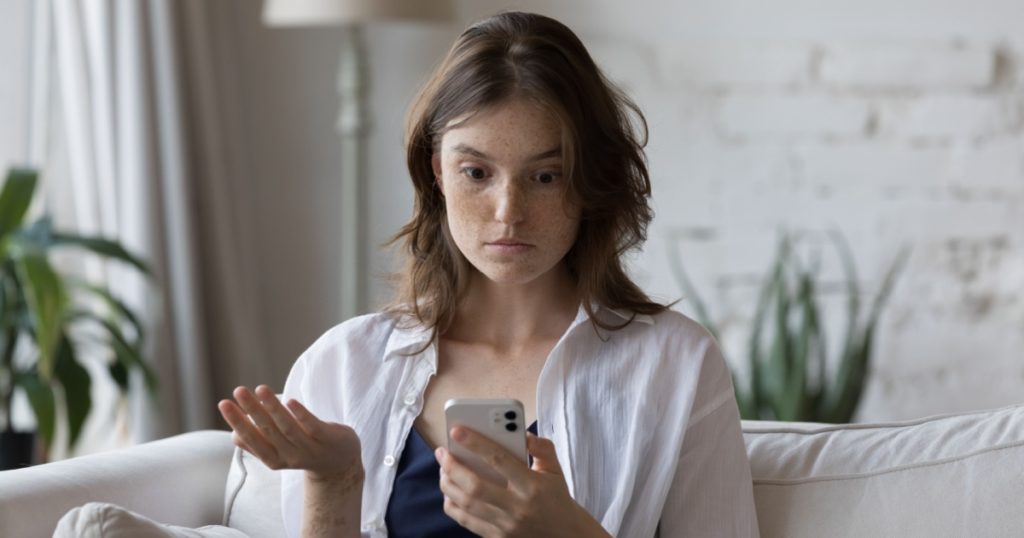 woman looking at phone in surprise