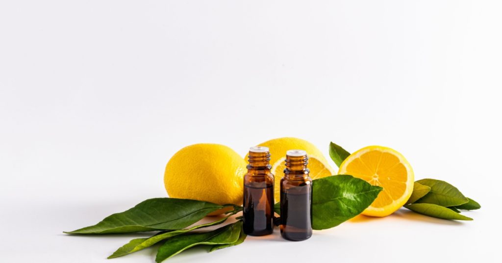 two bottles of dark glass on the background of ripe lemons and slices. lemon essential oil, lemon juice extracts, lemon essence for home use