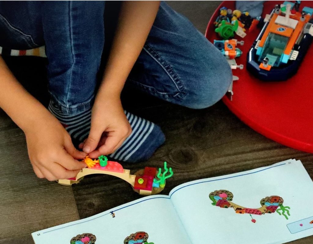 Boy doing Legos by following instruction manual.