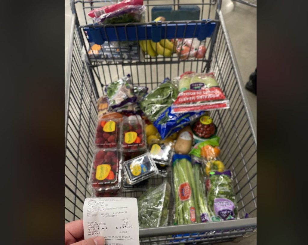 Aldi grocery cart full of raspberries, celery, bananas, and other fruits and vegetables. 