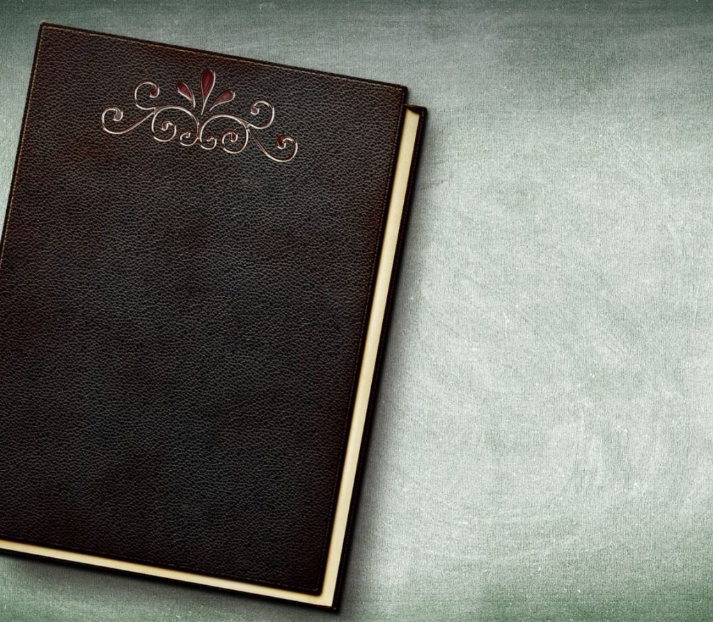 Leather bound book against a light green surface.