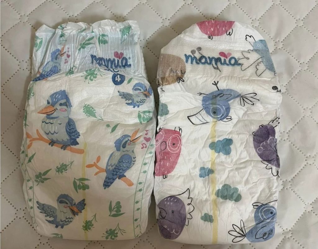 Two diapers side by side with birds, clouds, and branches. White checkered background. 