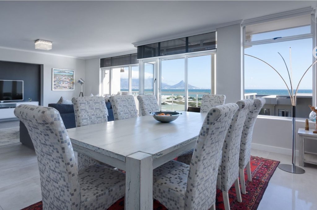 Large table overlooking ocean with mountain in the background. 