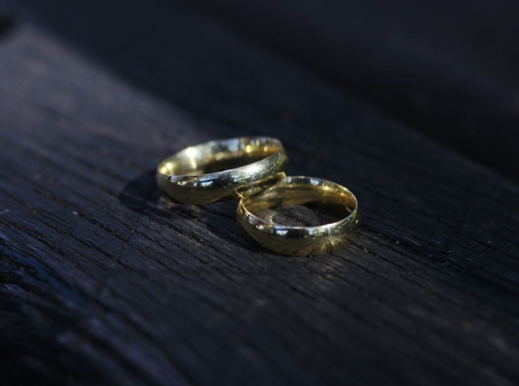 Two gold wedding bands on a black surface. 