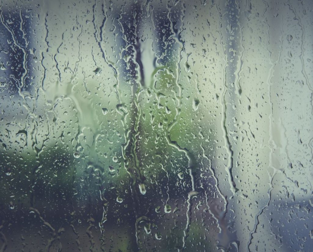 Window with rainwater falling. Burred background. 