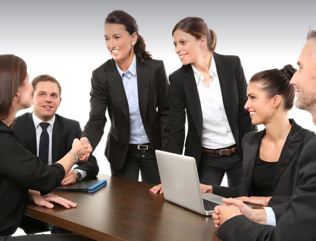 People in work attire gathered around a table.