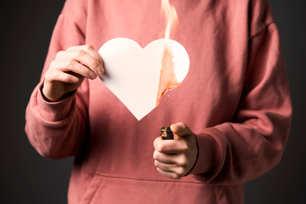 The woman sets the heart on fire, the end of the romantic relationship. Young girl sets fire to a white paper heart, declaring war on inequality in the toxic abusive relationship in which she was.
