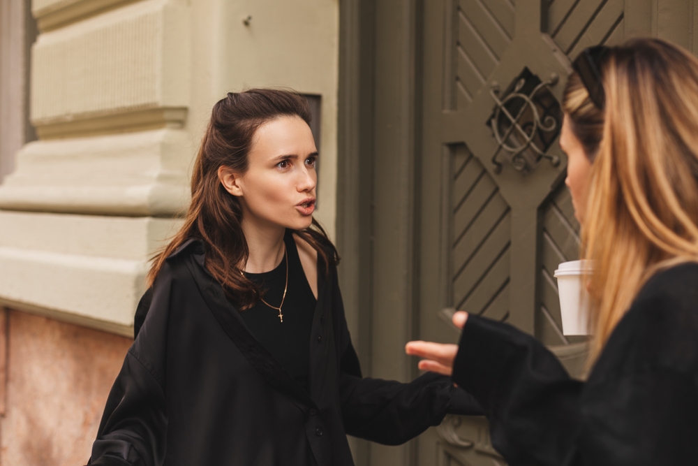 Quarrel two friends. Two women screaming at each other. Two young women argue near door outdoor on the street. Family problem. Angry female show emotion. Depression people. Stress family photo.