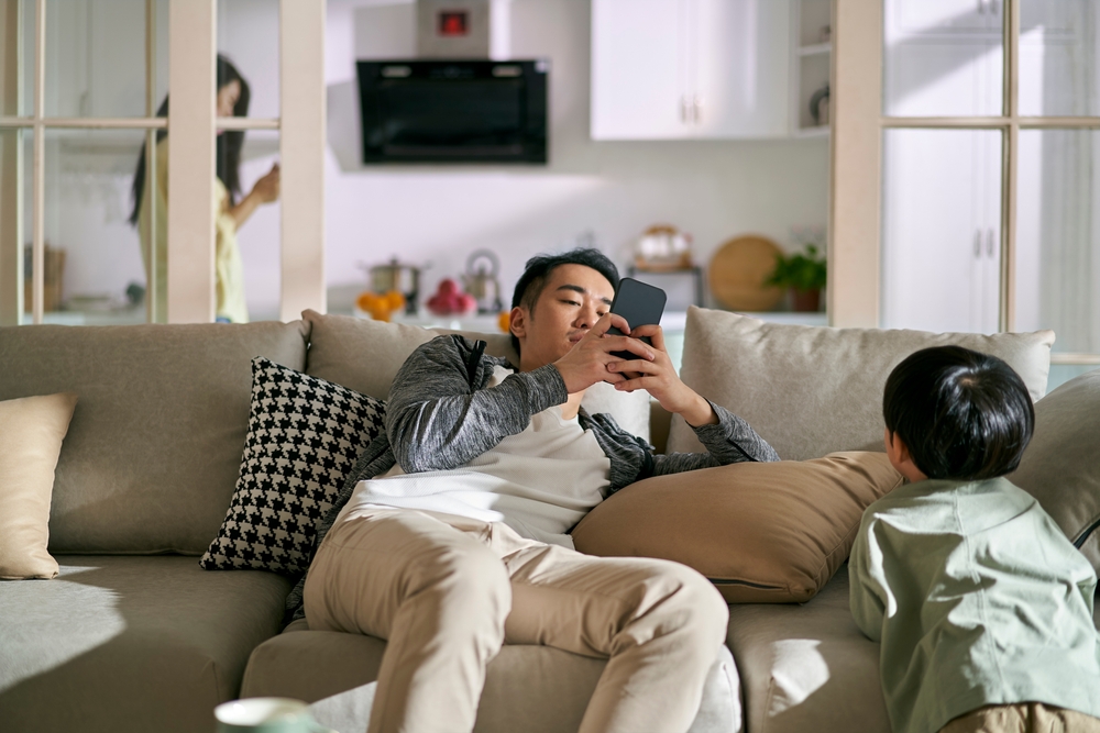 young asian couple parents addicted to smartphones ignoring child, concept for smartphone or social media addiction
