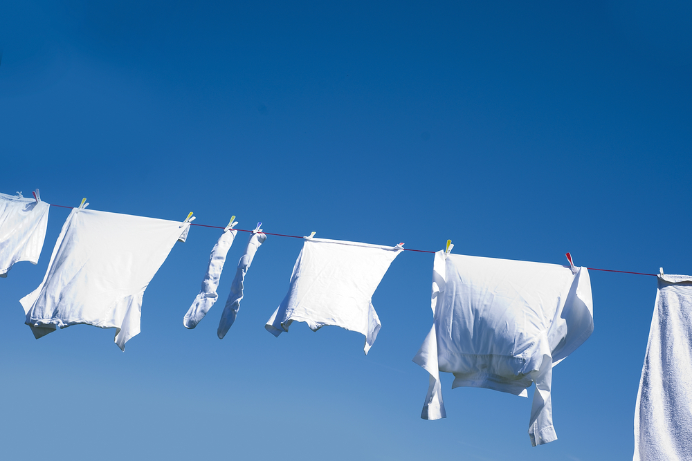 White clothes hanging on the line against blue sky.
