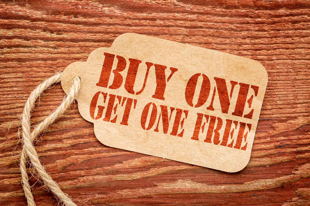 buy one get one free sale sign - a paper price tag against rustic red painted barn wood - shopping concept
