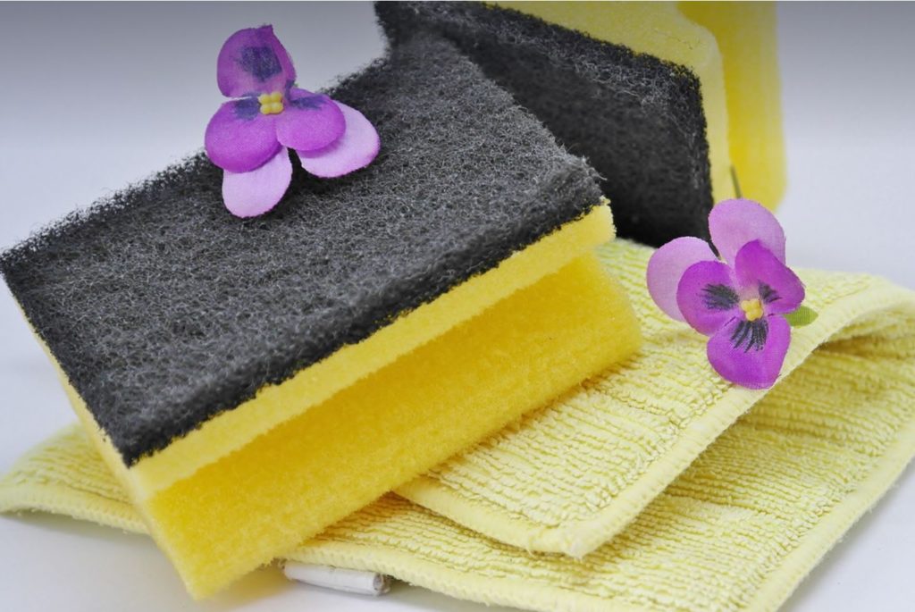 Kitchen sponge and towel with purple flowers. 