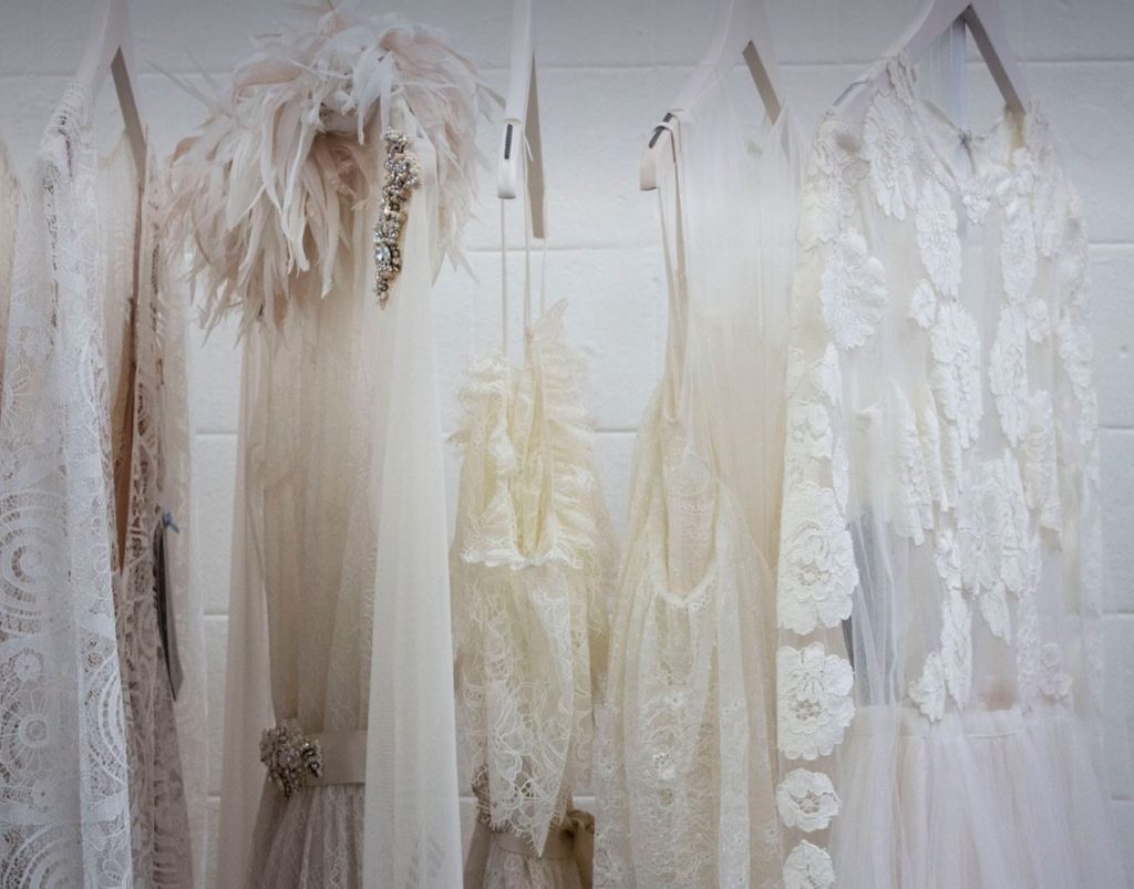 Closet with a few white and off-white dresses. 