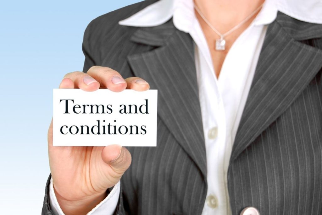 A woman in a blazer holding up a terms and conditions card. Blue background. 