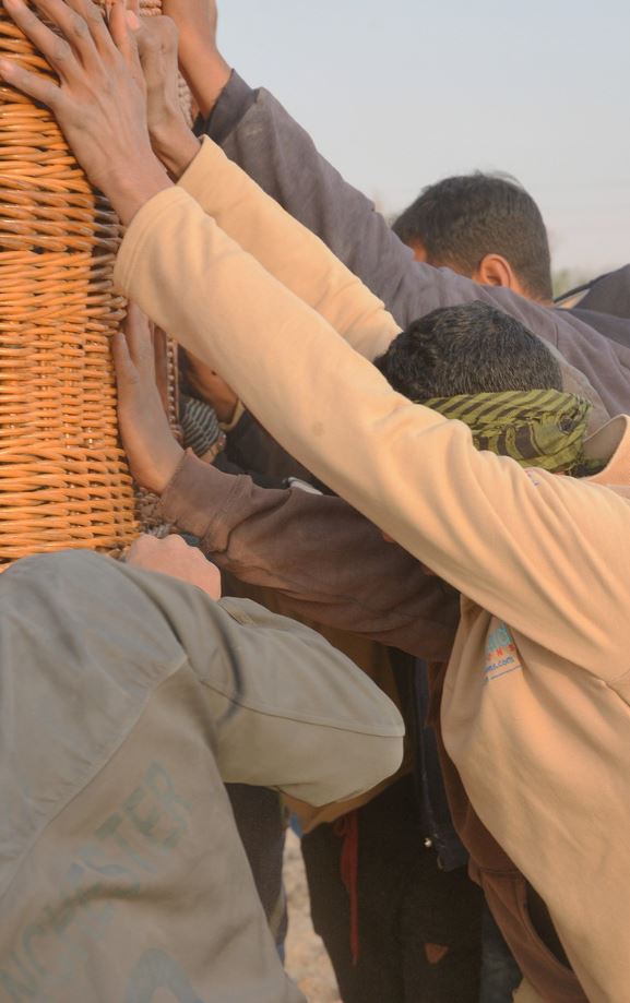 Men helping each other hold up large wicker backet.