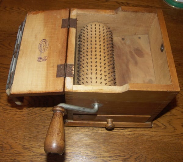 Old wooden box with a grater inside and a crank on the outside. 