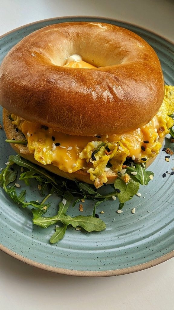 A bagel breakfast sandwich on a light green-blue plate.