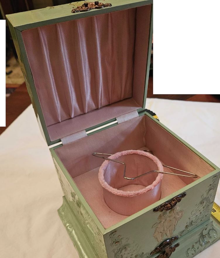 Wooden box painted green with hints of pink and gold.