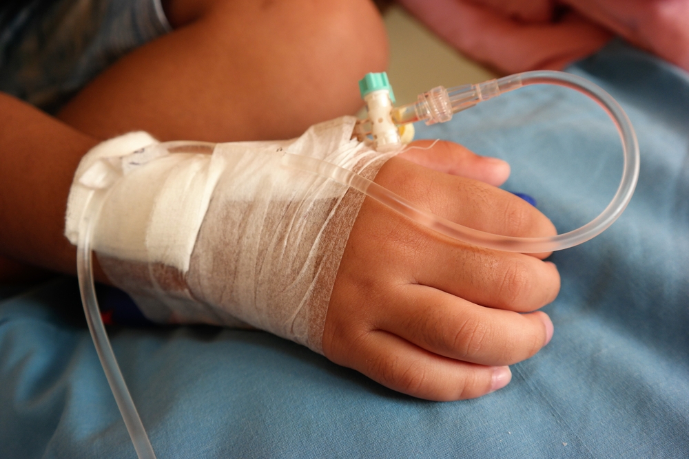 Asian baby in hospital with intravenous saline. Sick children, infected with the virus, are lying and being treated in beds in hospitals.