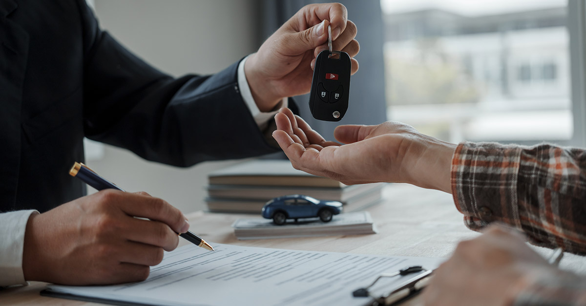 car sales person handing over keys to new owner