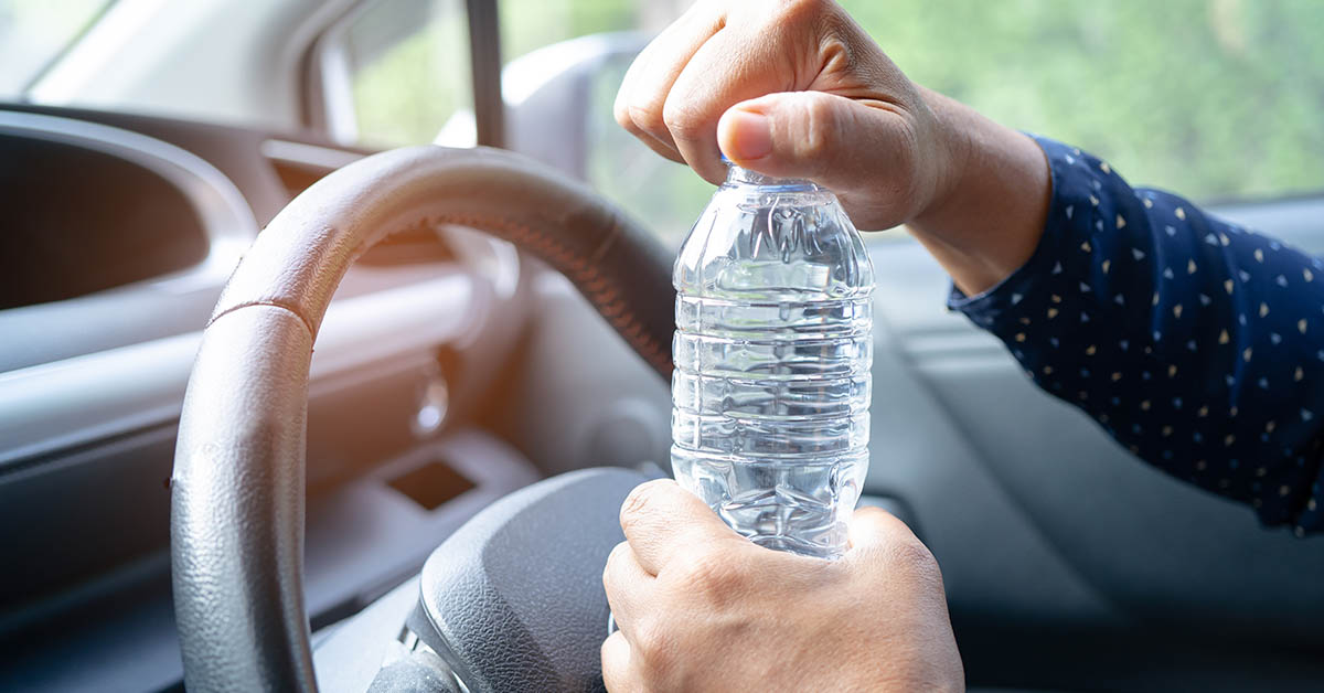 person opening bottle of water in a car