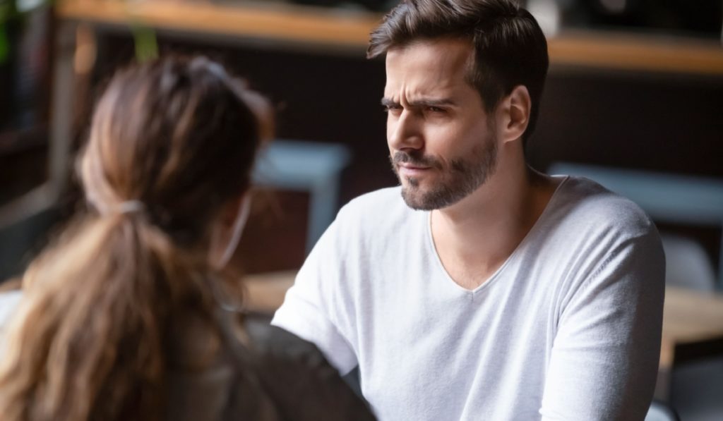 Doubting dissatisfied man looking at woman, bad first date concept, young couple sitting at table in cafe, talking, bad first impression, new acquaintance in public place, unpleasant conversation