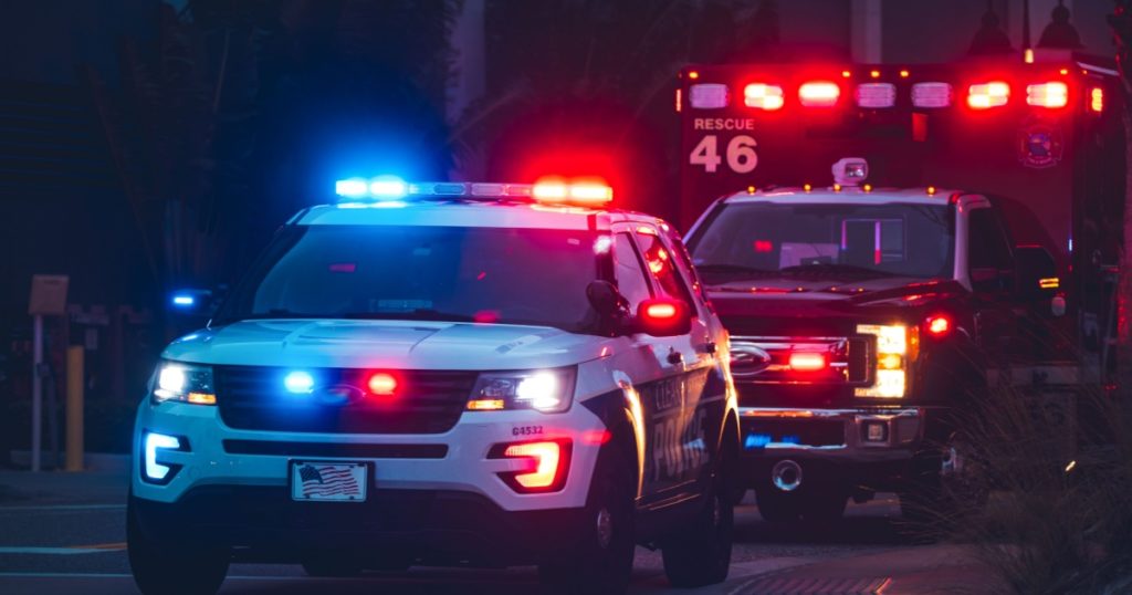 American Police Car and Emergency truck with Blue and red lights. US Paramedic Fire Rescue resuscitation help. Investigation Crime, murder, theft, police arrest. Photo has a dramatic toning.