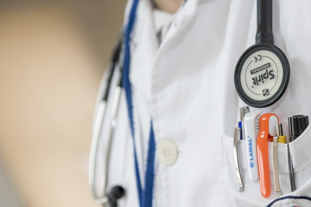 A close up of a doctor's coat, pocket with pens, and stethoscope.