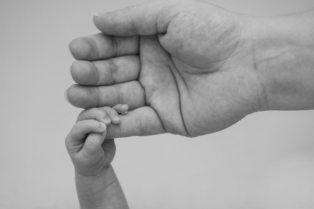 tiny hand holding an adult finger