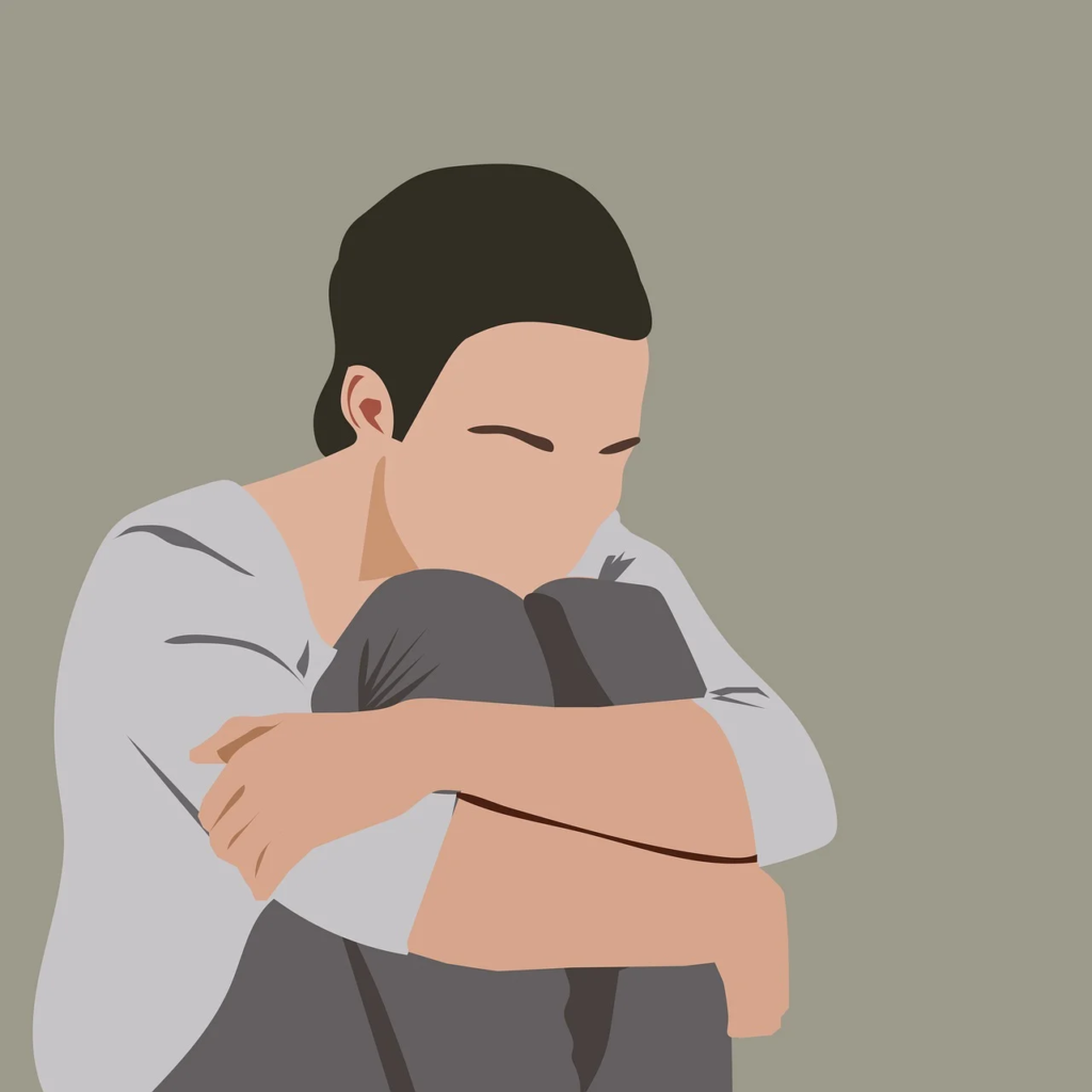 person sitting down hugging their legs