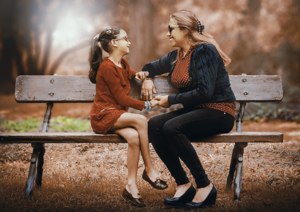 mother and daughter on a park bench holding hands