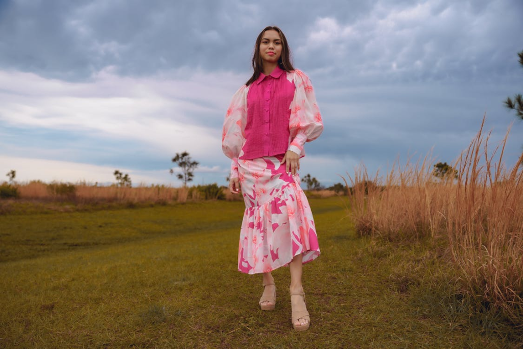 Young Woman in a Fashionable Pink Outfit Posing on a Field