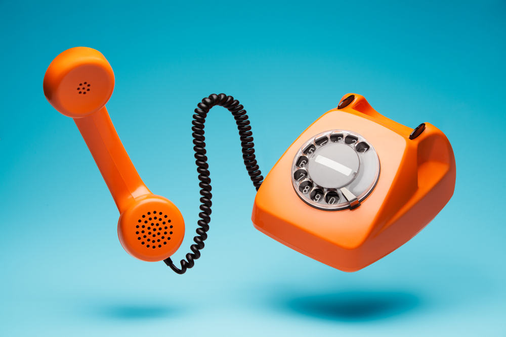 Old orange telephone rings with handset off.