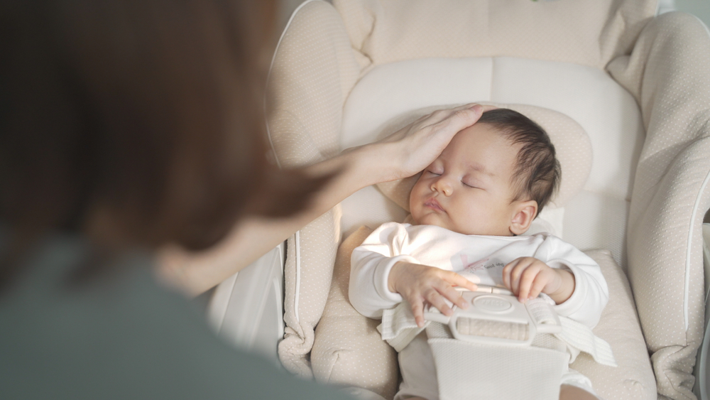 asian woman mother gently touching baby infant head with care lull to sleep on baby buggy at home. baby sleeping on baby stroller. natural authentic.