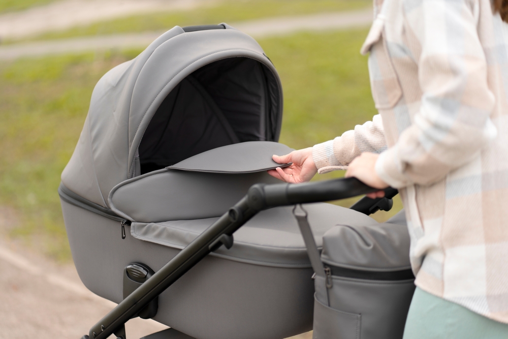 Closeup of woman looking at baby in troller while walking down city street. Concept of motherhood, parenthood