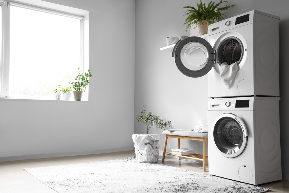 Interior of modern laundry room with washing machines and grey bench