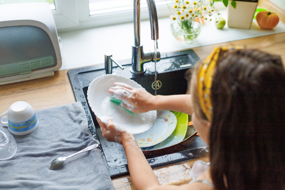 Getting chores done quicker together. Cropped shot of little daughter washing dishes together at home.
