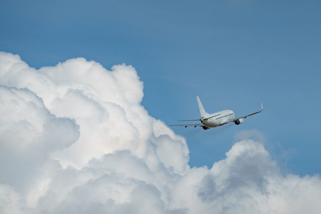 An airplane in the sky. White clouds and blue sky in the background. 