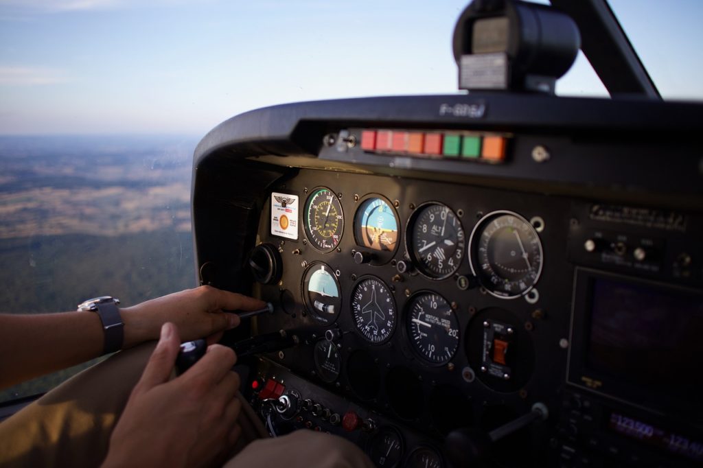 An airplane cockpit. Blurred mountains and sky in the background. 