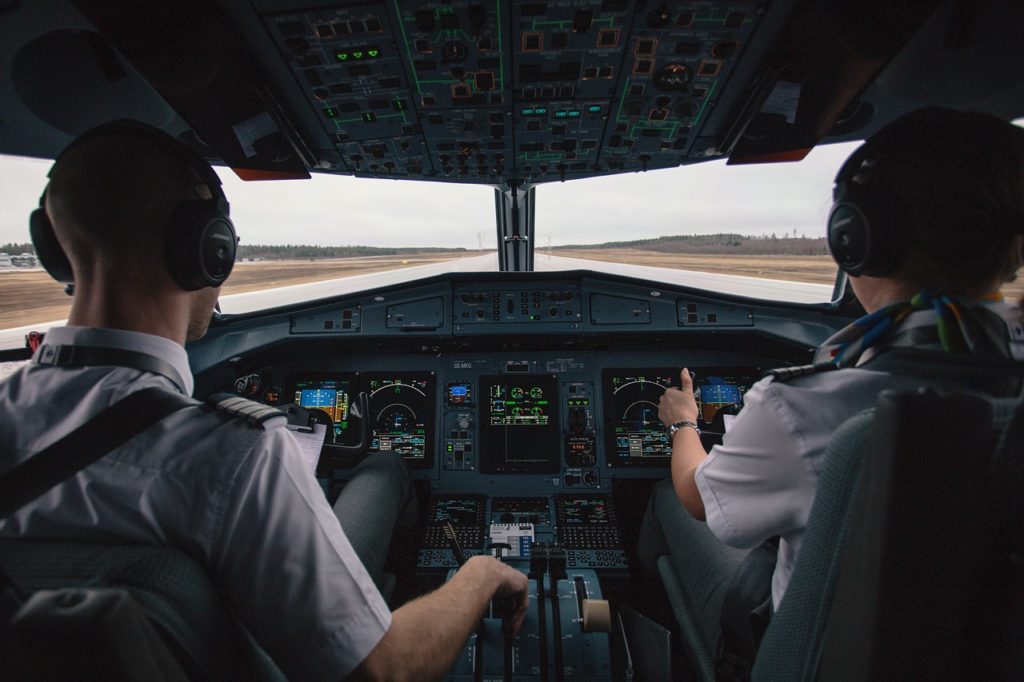 Two pilots in a cockpit. Runway in the background. 