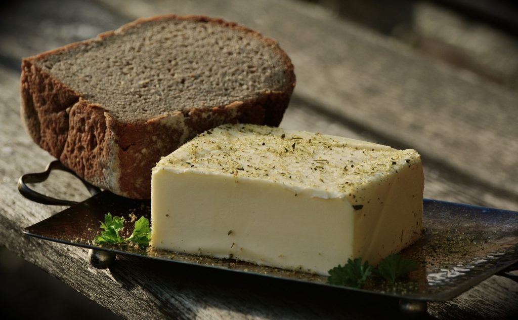 Seasoned butter and bread on a plate. Wooden background.