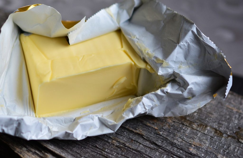 A block of butterin a wrapper. Wooden background.