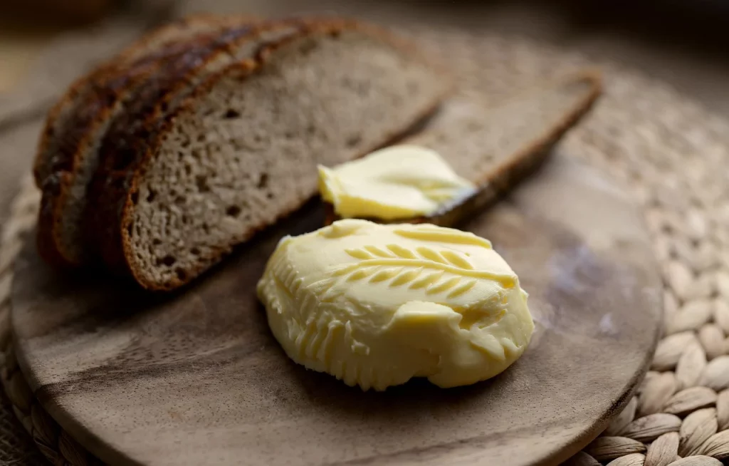 Decorative butter and bread on a wooden bread board. Textured background.