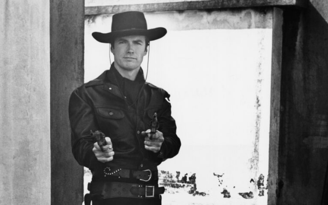 Actor Clint Eastwood as a gunslinging cowboy. He is pointing the guns he holds in each hand toward the camera.